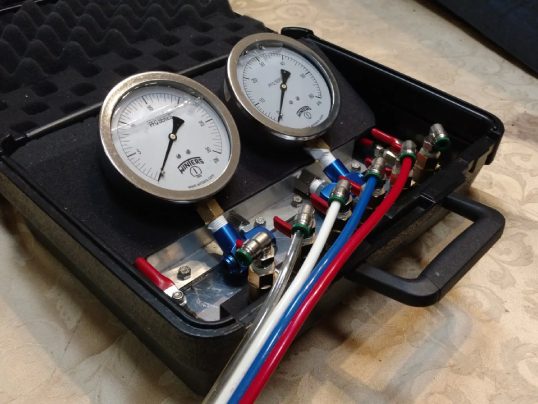 Two pressure gauges with colored hoses in case